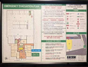 An example view of the evacuation plans and procedures near the lifts on each floor of the building, featuring a map, the text Emergency Evauation Plan, and some small text under headings Evauation Procedures and Standard Fire Orders. The lower right corner shows P.M.C. Drafting Services